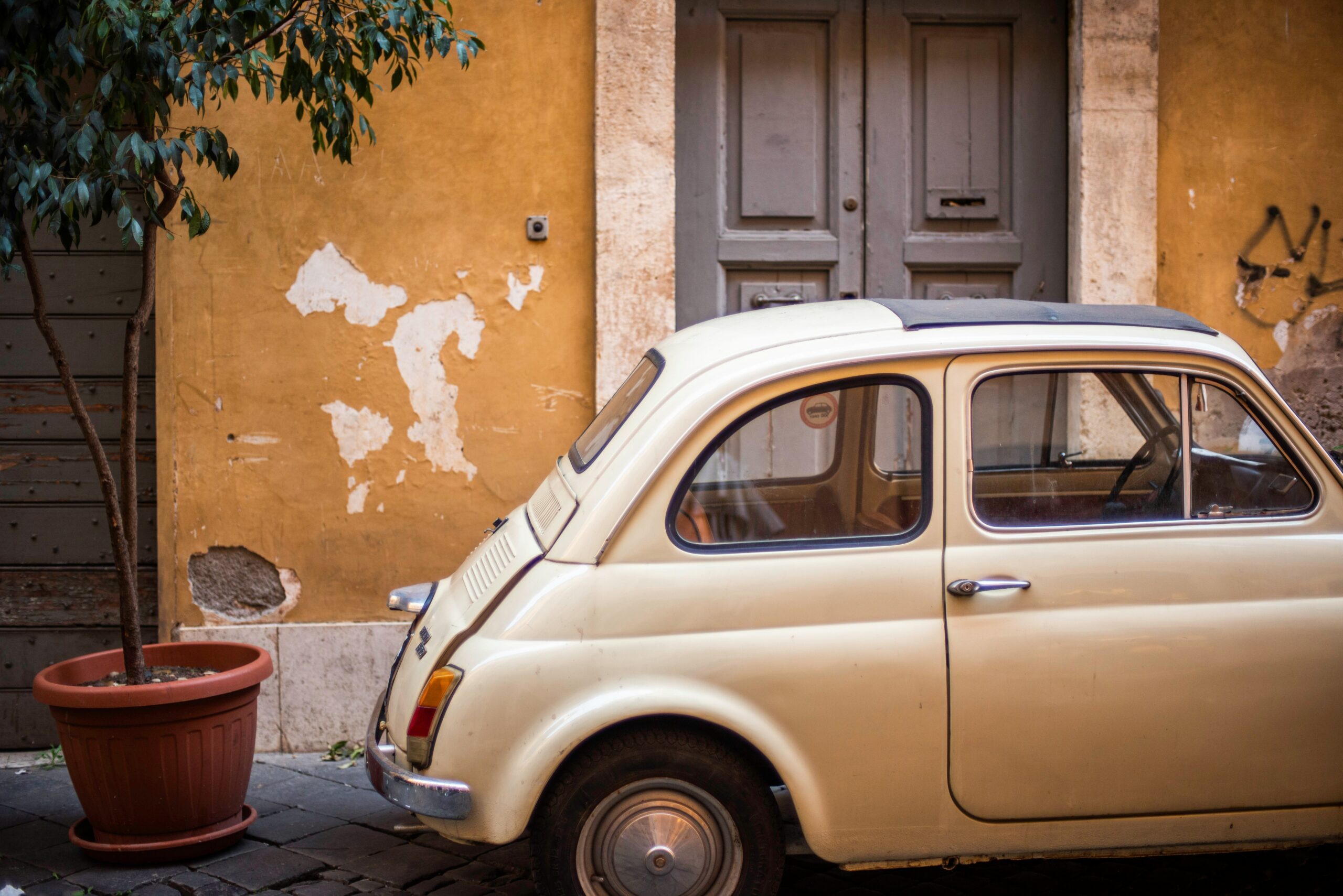 Vintage cream Fiat parked in front of a weathered ochre building